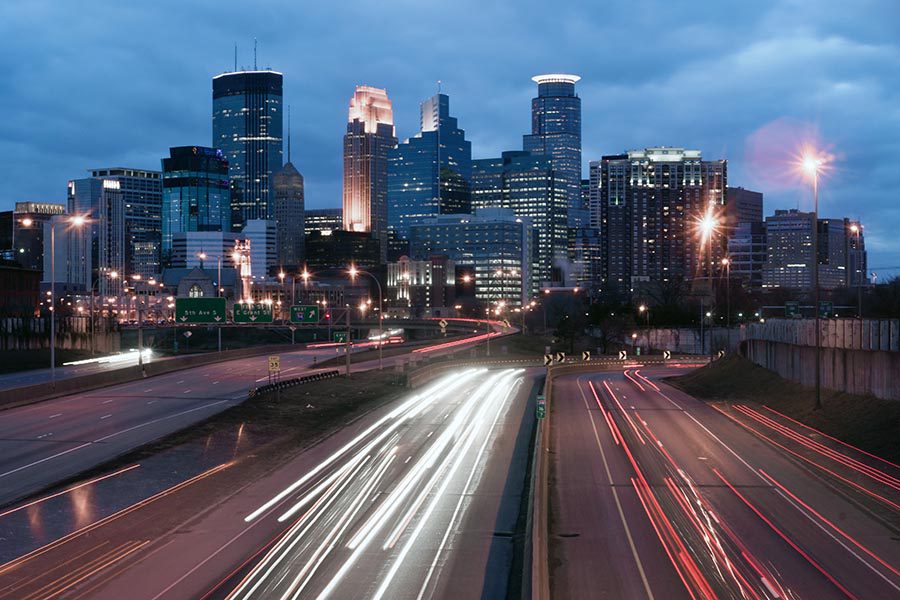 Contact - Long Exposure Image of Minneapolis, Minnesota Seen From the Highway, With Cars Zooming in and Out of the City, and the Buildings Lit up for the Evening
